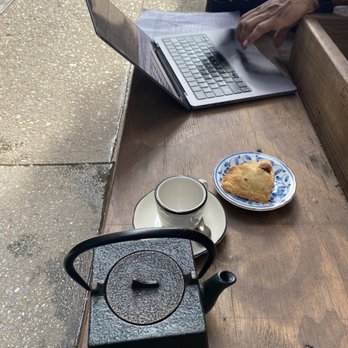 Paquita - Japanese tea pot with tea and a scone outside in a bench, with a neighbor working on a computer - Tea Rooms Near Me - New York, New York