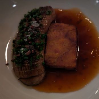 Ariete - A dish with a piece of seared fish, garnished with chopped herbs, served in a shallow bowl with a brown sauce. - New American Near Me - Miami, Florida