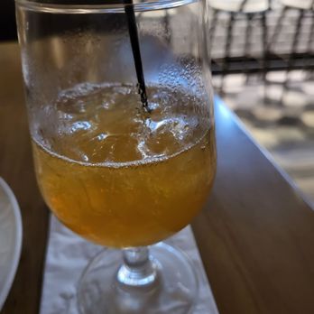 Amuse - Amaretto sour - A tall glass contains an amber-colored amaretto sour with ice, a black straw, and condensation on the outside, placed on a napkin at a restaurant or bar. - Bars Near Me - Parsippany, New Jersey