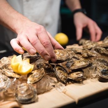 Cassis Bistro - a chef slicing oysters on a cutting board - French Near Me - Calgary, Alberta