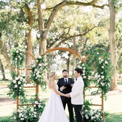Custom wedding ceremony arch with ivory and white flowers and seasonal greenery