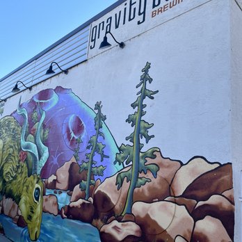 Sunday Bagels - Located at Gravity Bound - A colorful mural depicts a natural landscape with trees, rocks, a stream, and a creature with a dinosaur-like head, on the exterior wall of a building labeled 'gravity bound BREWING CO.' - Bagels Near Me - Albuquerque, New Mexico