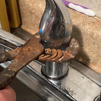 Pipeworks Services - pliers slipped on round  housing which instructions say "hand tighten". - A rusted pipe wrench is gripping a rusted pipe beneath a kitchen sink faucet with a chrome finish. The faucet is mounted on a granite countertop, and the surrounding area shows signs of corrosion and wear. A toothbrush is visible on the countertop, indicating a kitchen setting. - Heating & Air Conditioning/HVAC Near Me - Gaithersburg, Maryland