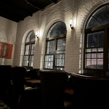 Conspiracy - a dimly lit room with several windows - Cocktail Bars Near Me - Middletown, Connecticut