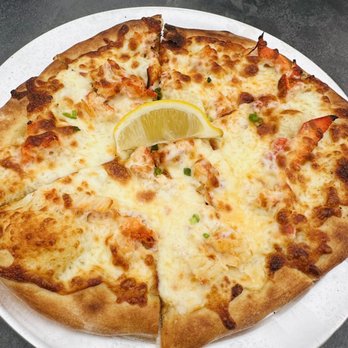 Patio 03907 - Lobster pizza - A cheese pizza with melted cheese and a lemon wedge on top, garnished with small green herbs, served on a white plate. - Seafood Near Me - Ogunquit, Maine