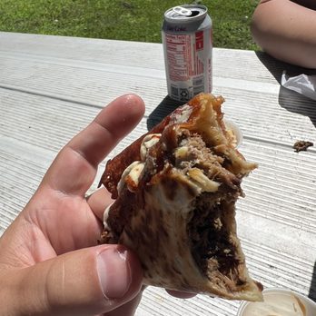 Chops Taco - a hand holding a half eaten sandwich - Food Trucks Near Me