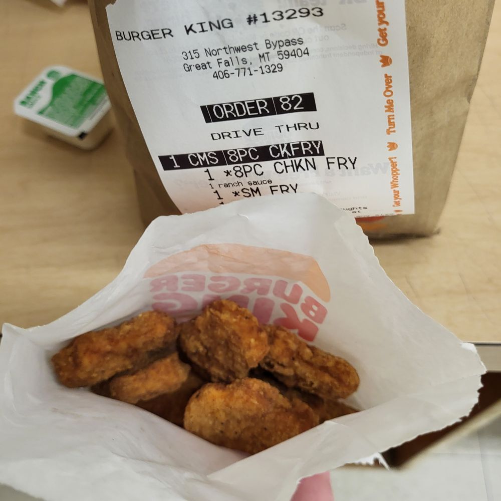 a hand holding a basket of fried chicken nuggies