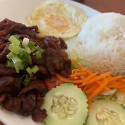 Bbq pork, egg over hard, veggie salad and an egg roll with white rice.