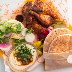 Our most popular menu item: the quarter plate with rotisserie chicken, wedge salad, hummus, pickles, pita, chili oil, and garlic sauce.