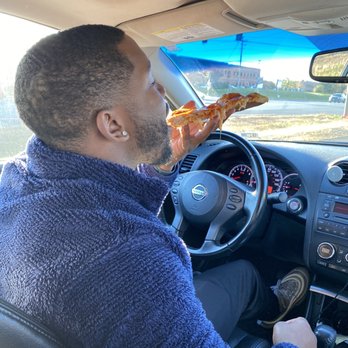 Rai's Pizza - a man eating a slice of pizza - Chicken Wings Near Me - Sterling, Virginia