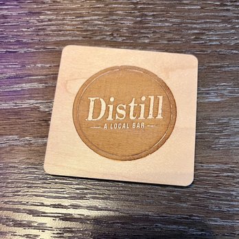 Distill - Inspirada - a wooden coaster with a logo on it - Sports Bars Near Me - Henderson, Nevada