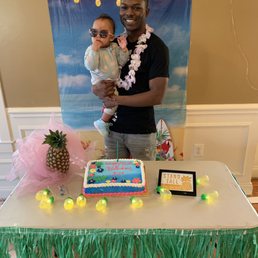 a man holding a baby in front of a cake a man holding a baby in front of a cake