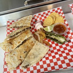 Tacos Estilo Chavinda - This is our steak quesadilla. Along with grilled onions, grilled green pepper, radishes, lemon, tortilla chips, and red sauce.