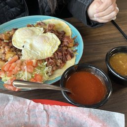 Juevos rancheros with bacon, red and green chili on the side.