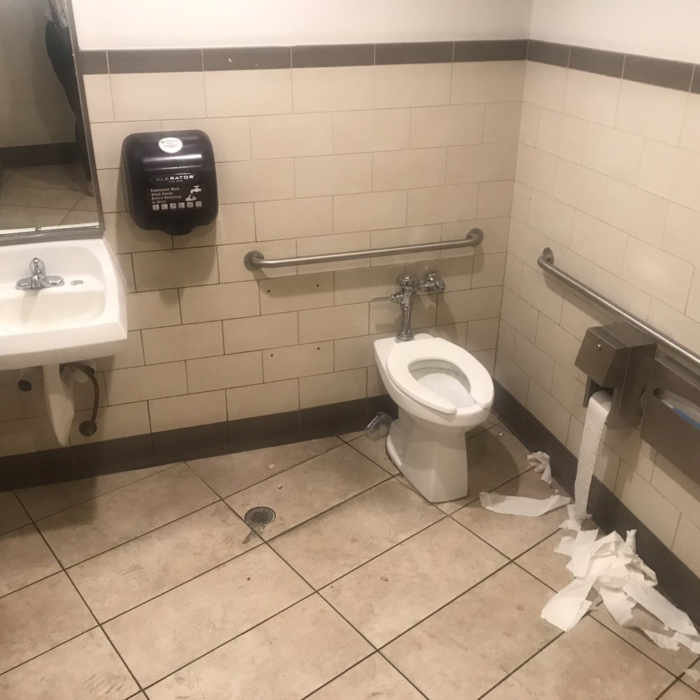 A sink with wet paper towels, a drink spilled on the floor with wet toilet paper! Ladies do Better‼