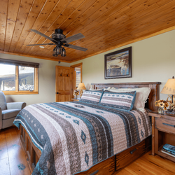 The Inn at Oxbow Acres - Room with king size bed, wooden nightstands, and large armchair.