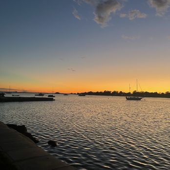 Warren Town Beach - A sunset scene over a body of water with boats anchored near the shore and a partly cloudy sky. - Beaches Near Me - Warren, Rhode Island