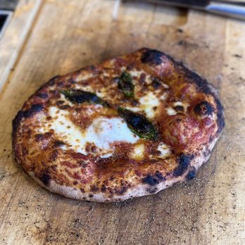 ooni - My  Margherita Pizza! Still photo :) Ooni has a learning curve but my son and i rocked it!!!! - A Margherita pizza with melted cheese, tomato sauce, and basil leaves on a wooden pizza peel. - Grilling Equipment Near Me - El Paso, Texas