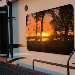 Hickory Hills Campground - Lovely sunrise and many large trees reflected from a camper window.