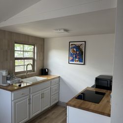 A kitchenette with cabinets and a sink in front of a window