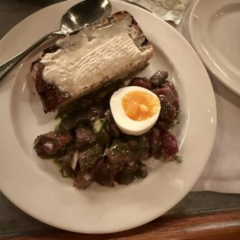 Pitt's - Bison tartare - A dish featuring a slice of Bison tartare with a creamy topping, a halved soft-boiled egg, and a salad with chopped vegetables on a white plate. - New American Near Me - Brooklyn, New York