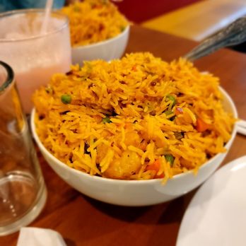 Spice House - Shrimp Fried Rice - A large bowl of shrimp fried rice with vegetables such as peas and carrots, served on a wooden table in a restaurant setting. - Indian Near Me - Edison, New Jersey