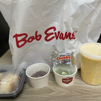 Bob Evans - Potato Cheddar Soup with biscuits, bacon & scallions, Excellent. Thank you & the young girl excelled in customer service. - A collection of food containers from Bob Evans, featuring potato cheddar soup, a biscuit, a small salad, a snack bar, and a dessert, on a wooden table. - Breakfast & Brunch Near Me - Aberdeen, Maryland