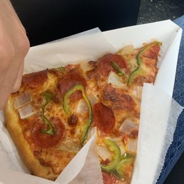 Pizza by the slice - A pizza slice topped with pepperoni, green peppers, and onions, served in a white pizza box.