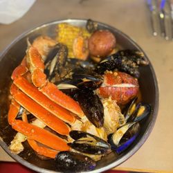 A combination of lobster, snow, crabs, muscles, headless shrimp, two pieces of corn and three potatoes