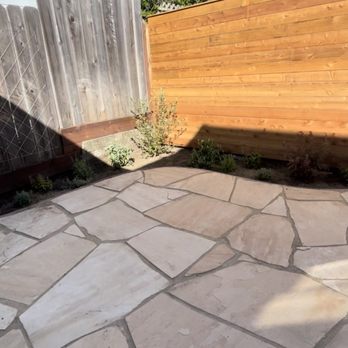 Tin Landscaping - a stone patio with a wooden fence - Landscaping Near Me Tin Landscaping - a stone patio with a wooden fence - Landscaping Near Me