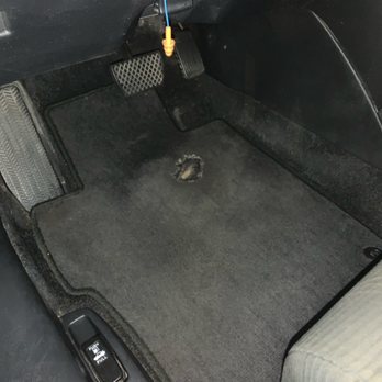 Lucid Auto Detailing - The image depicts the driver's side floor area of a vehicle, with a worn hole in the carpet near the center. - Auto Detailing Near Me - West Allis, Wisconsin