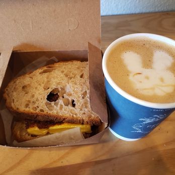 Perenn - Midtown - Breakfast sandwich with bacon jam, egg soufflé and cheddar. Coconut orange blossom latte with cute rabbit : ) - Bakeries Near Me - Reno, Nevada