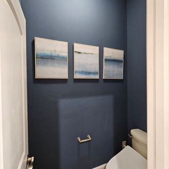 Angel Painting - Small powder room featuring rich navy blue painted walls, white trim, modern artwork, and clean fixtures, creating a sophisti... - Painters Near Me Angel Painting - Small powder room featuring rich navy blue painted walls, white trim, modern artwork, and clean fixtures, creating a sophisti... - Painters Near Me