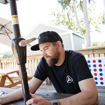 Brew Link Brewing - The Husband looking over the menu with a cool outdoor game behind him. - Breweries Near Me - Plainfield, Indiana