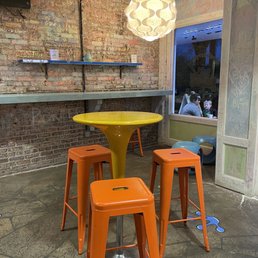 a yellow table and four orange stools