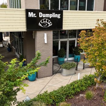 Mr Dumpling - The image shows the exterior of Mr. Dumpling restaurant with a black sign, large windows, and landscaped plants and trees. - Dim Sum Near Me - Eugene, Oregon