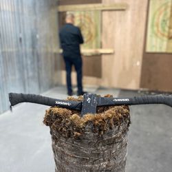 The Axe Hole House - Large axes on their base with targets in background. They have to be watered down every 10 min to keep wood soft.