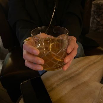 The Cannon Room - a person holding a glass of alcohol - Whiskey Bars Near Me - Baltimore, Maryland
