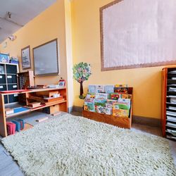 Temecula Montessori Academy - A cozy reading corner featuring a soft, fluffy rug, a bookshelf brimming with books.