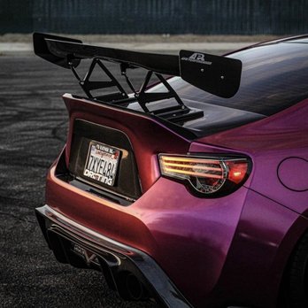 Hex Creations - A purple sports car features a prominent rear wing, custom California license plate, and sleek taillights, parked on a dark surface. - Vehicle Wraps Near Me
