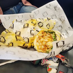 a burrito wrapped in wrapper and sitting on a table a burrito wrapped in wrapper and sitting on a table