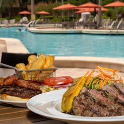 Chimichurri Steak and Avocado Salad and Harry's Burger on a poolside table.