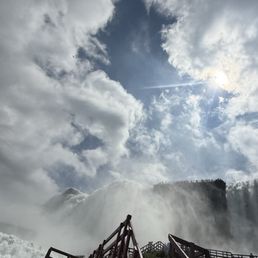 Upward angle of falls misting the air. In front, there's a staircase to climb that takes guests closer to the misty areas.