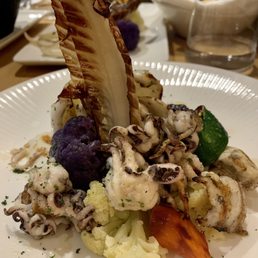 Octopus on top of mashed potatoes with vegetables