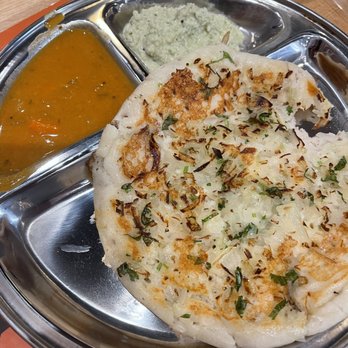 Malgudi Cafe - Onion Dose, Spongy and Yummy! - A stainless steel tray holds a stuffed naan topped with herbs, a serving of curry, and a side of chutney, typical of South Indian vegetarian dishes. - Indian Near Me - Exton, Pennsylvania