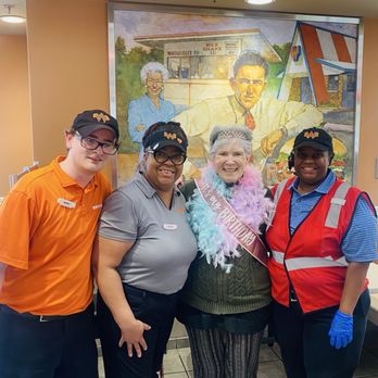 Whataburger - A woman wearing a birthday sash and feather boa is surrounded by three staff members in uniform at Whataburger, Tomball, TX. - Burgers Near Me - Tomball, Texas
