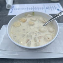Clam Chowder - A bowl of clam chowder with a spoon, placed on a tray with a napkin, at Patio 03907 in Ogunquit, ME.