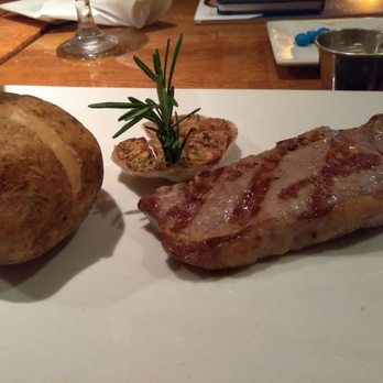 Raindancer Steakhouse - Aged strip steak with baked potato and roasted garlic - Steakhouses Near Me - West Palm Beach, Florida Raindancer Steakhouse - Aged strip steak with baked potato and roasted garlic - Steakhouses Near Me - West Palm Beach, Florida