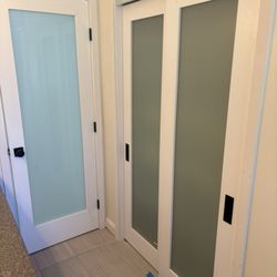 The Unhinged Door - Frosted glass bathroom door and linen closet doors give this such a Beautiful modern touch.