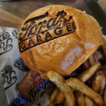 Ford's Garage Florence - Brisket burger - A burger with a branded bun labeled 'Wicked Good' is served with seasoned French fries on a tray at a restaurant. - Burgers Near Me - Florence, Kentucky